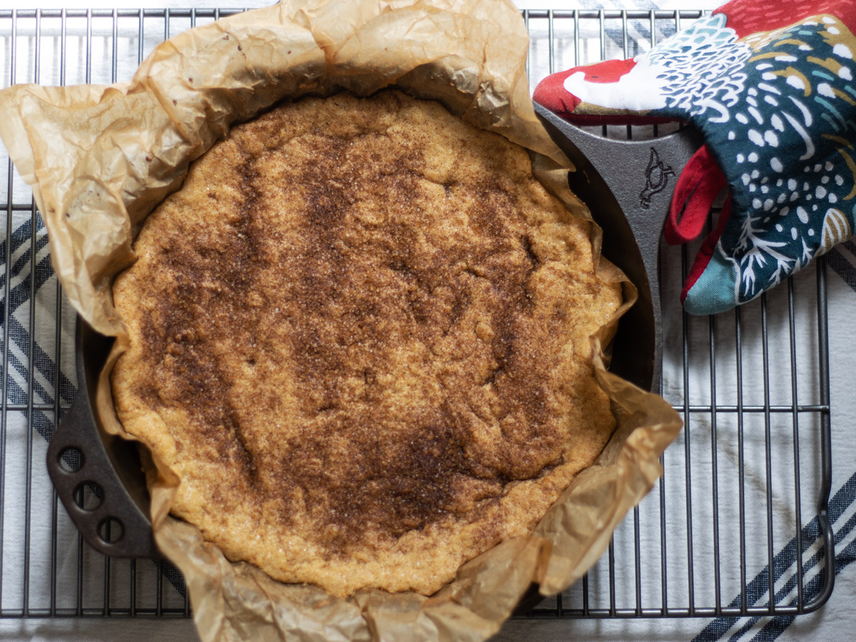Snickerdoodle bars cooling in a cast iron skillet on a rack
