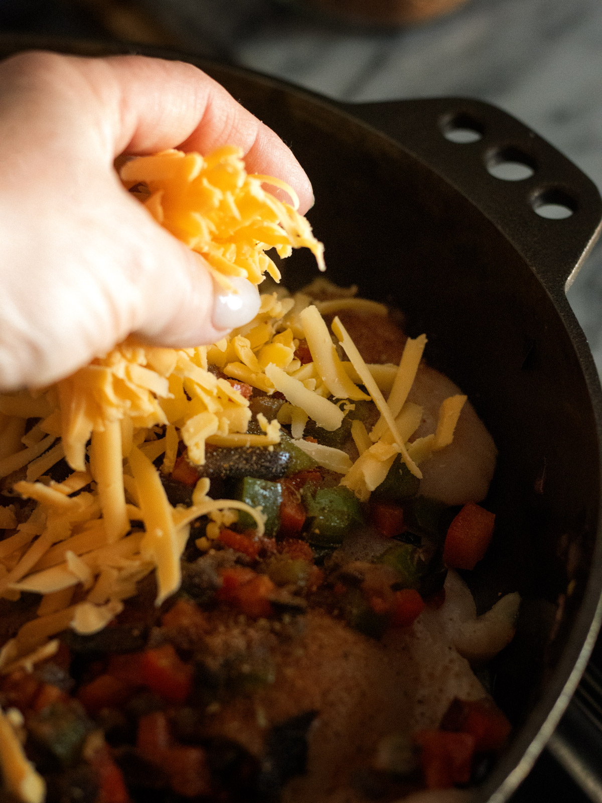 spreading cheese on the Cajun chicken